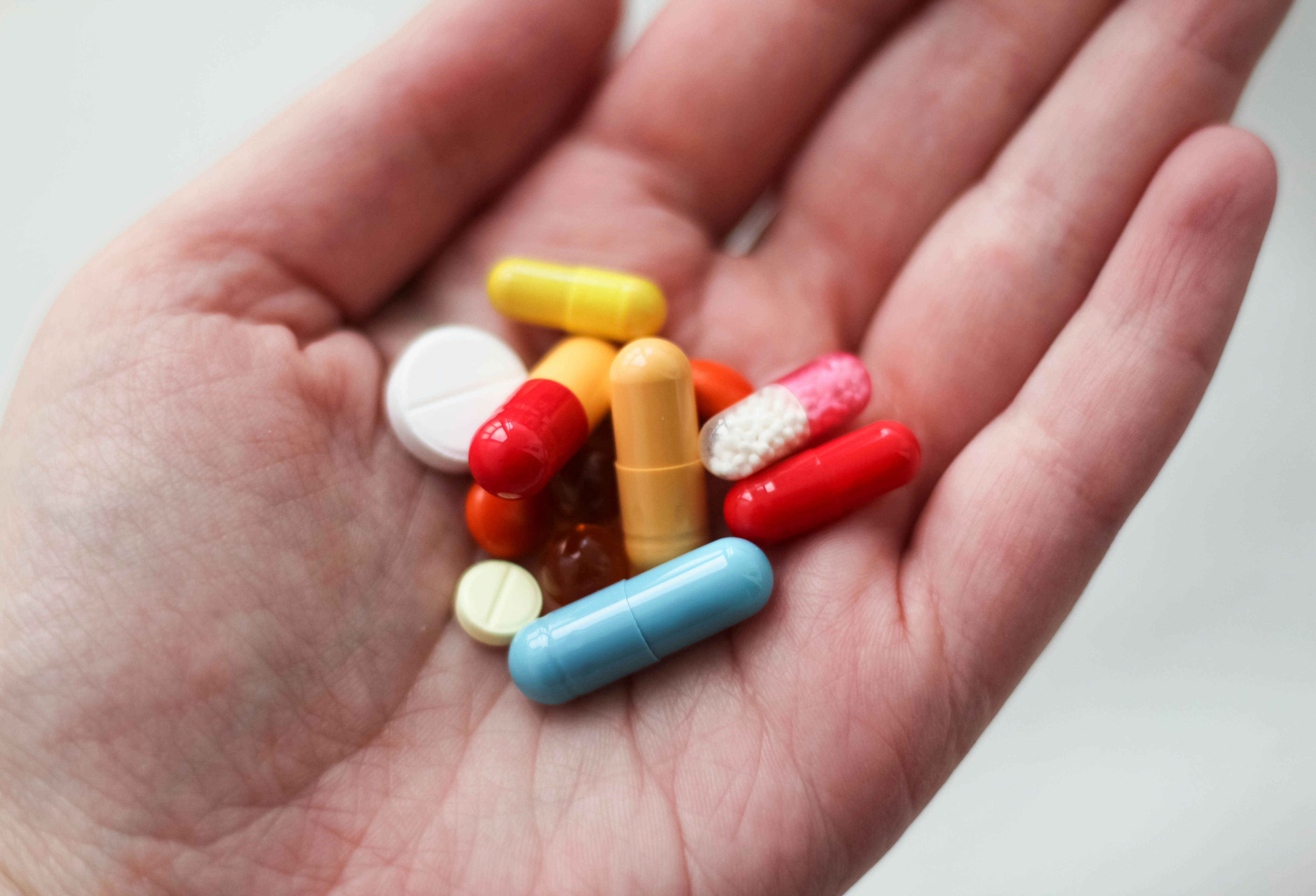 Hand vol pillen met allemaal verschillende medicatie.